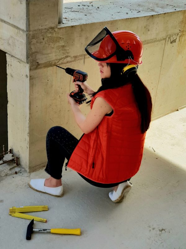 a woman sitting on the ground holding a drill